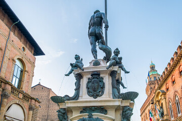 Obraz premium Fontana del Nettuno on Piazza del Nettuno in Bologna old town, Emilia Romagna, Italy. Main square Piazza Maggiore with bronze statue Fontain of Neptune against colorful medieval buildings