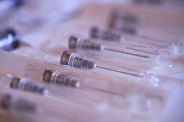 Close up of a group of hypodermic syringes on a white surface