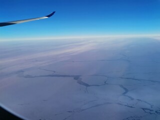 Airplane window view ocean and ice