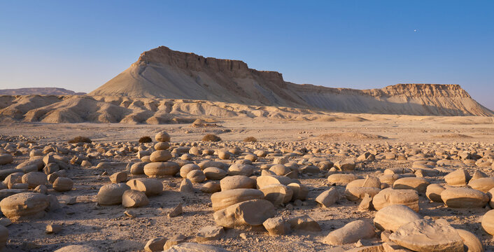 Mount Tzin or Har Zin in Negev Desert. The large field full of medium sized rounded stones called Potato Field, in foreground. Unique landscape of the mount - sloped sides and a top like flat table