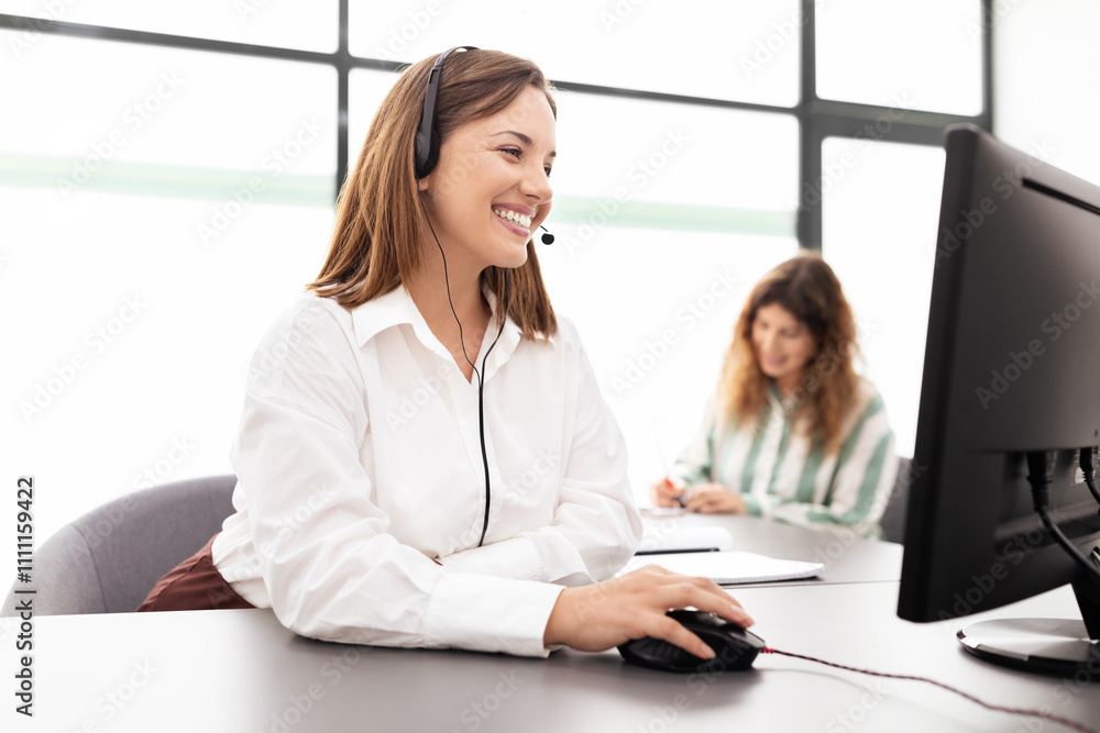 Poster two businesswomen are actively engaged in a corporate office setting. one is using a headset while o