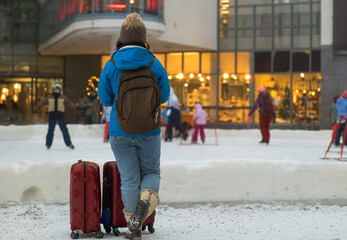 Traveler Observing an Outdoor Winter Activity Scene with Luggage