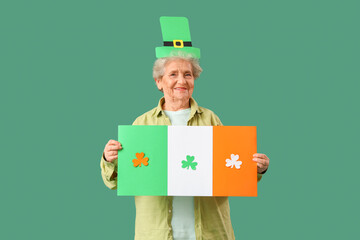 Happy senior woman in leprechaun hat with paper Irish flag for St. Patrick's Day celebration on...