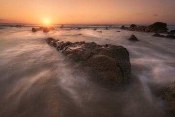 Obraz premium Sunset on Barrika beach, Bizkaia with the waves of the Cantabrian Sea breaking between the rocks