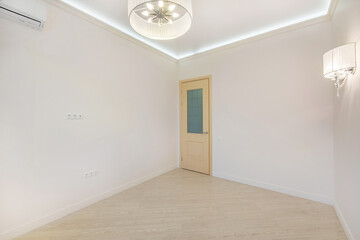 A spacious, empty, bright room with laminate flooring and a beige door.