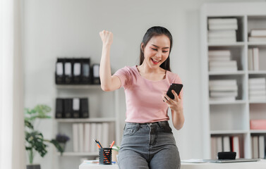 Joyful Success: Young Woman Celebrating on Smartphone