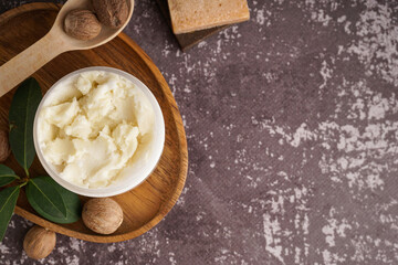 Jar of shea butter and nuts on grunge color background