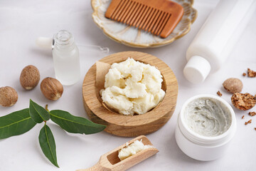 Composition with shea butter, hair comb and cosmetic products on light background