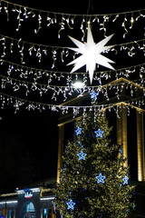 A beautiful evening scene in the center of Tbilisi with a large Christmas tree adorned with bright,...