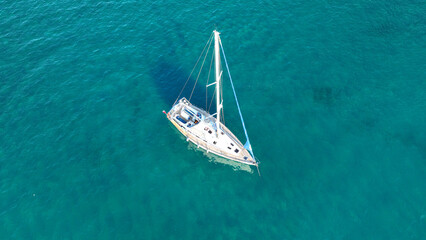 Fototapeta premium Aerial drone photo from tropical exotic paradise secluded rocky island bay with deep turquoise sea forming a blue lagoon visited by yachts and sail boats in Caribbean exotic destination