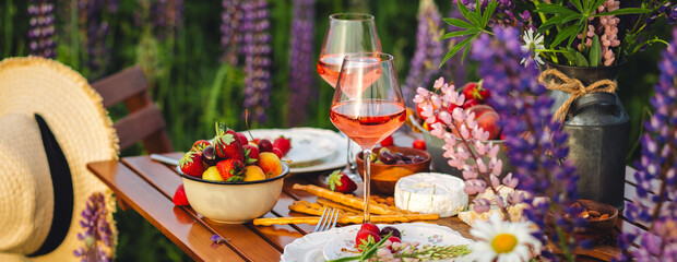 Banner. Perfect surprise date for loving couple, private wedding, romantic marriage proposal. Summer, sunset, golden hour. Beautiful elegant outdoor arrangement in meadow with purple blue lupins