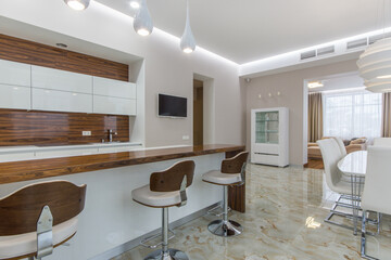 Spacious bright kitchen dining room with white furniture. Bar stools at the brown counter