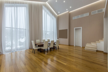 A luxurious living room of a country house with high ceilings, parquet floors and panoramic windows.