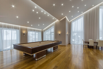 The open space of the living room of a private house with a high ceiling, large windows, .parquet floors and furniture.