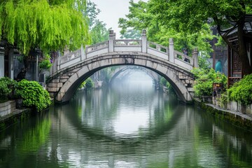 Naklejka premium Stone arched bridge over tranquil, green canal.