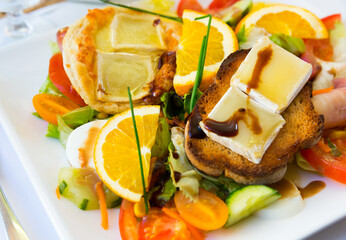 Salad with goat cheese, orrange, honey and vegetables at plate, dish of french cuisine