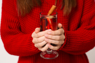 Young woman holding glass cup of hot mulled wine, closeup