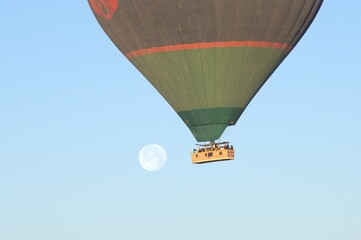 A hot air balloon is flying in the sky with a full moon in the background