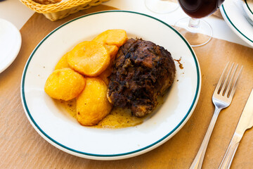 Fried pork with potatoes on a ceramic plate cooked in a restaurant
