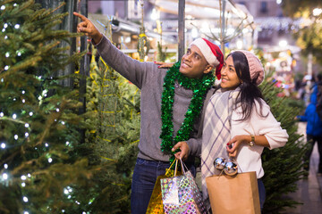 Family couple choosing christmas tree at christmas street fair