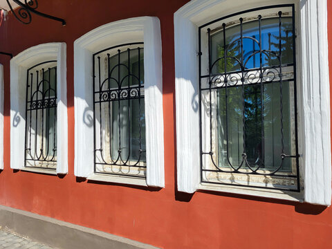 The facade is red with white windows and wrought iron grilles.