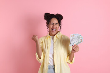 Happy woman with dollar banknotes on pink background