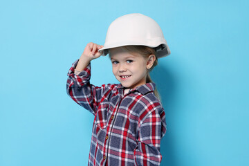 Little girl pretending to be architect on light blue background. Dreaming of future profession