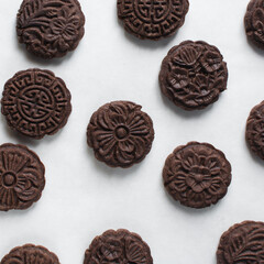 Overhead view of stamped chocolate cookies on a parchment lined baking tray, top view of embossed chocolate sugar cookies on a white background