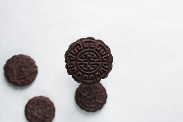 Overhead view of stamped chocolate cookies on a parchment lined baking tray, top view of embossed chocolate sugar cookies on a white background