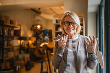 mature woman entrepreneur left voice mail on cellphone at rustic shop