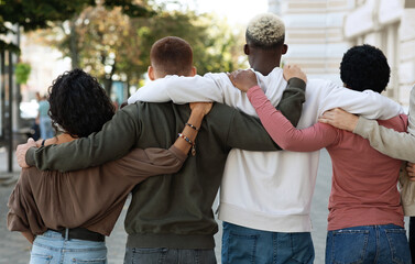 Back view of international group of people making strike on the street, hugging, showing their...