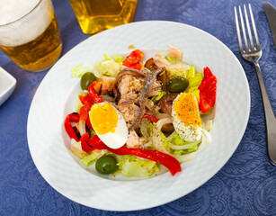 Light appetizing vegetable salad with tuna, made from lettuce leaves, red sweet pepper, onion, olives, eggs and fish