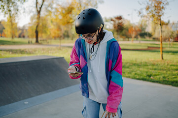 Skater using smartphone in skate park on sunny day