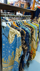 Colorful batik shirts hanging on a rack. Close-up shot highlights intricate patterns and vibrant colors. Perfect for fashion blogs or promoting Indonesian culture