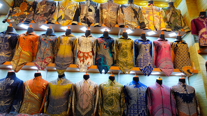 Colorful batik shirts on display in a shop. Selective focus on the shirts, low-angle shot emphasizes variety. Perfect for fashion blogs or promoting Indonesian culture.