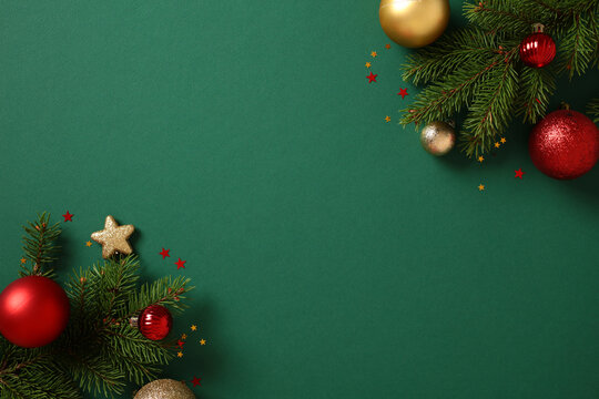 Christmas background with pine decor and vibrant baubles on green. Xmas greeting card template. Flat lay, top view, copy space.