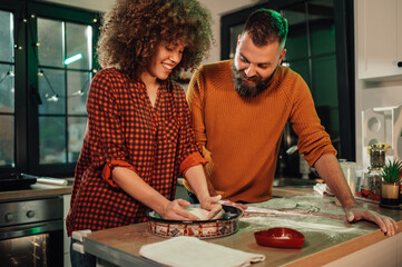Happy couple preparing dough in kitchen for baking together