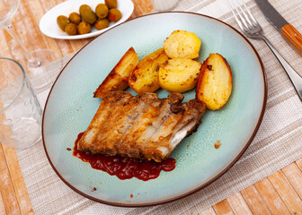 Grilled pork ribs rack with barbecue sauce garnished with potatoes