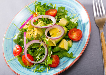 Appetizing salad with avocado, arugula and cherry tomatoes served on plate