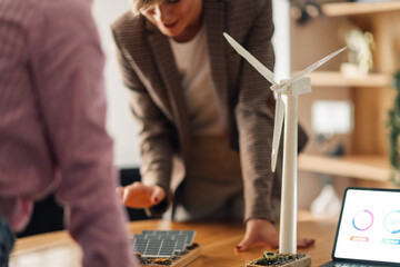 Engineers analyzing miniature wind turbine and solar panel for renewable energy project