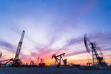 Obraz premium in the evening, oil pumps are running, The oil pump and the beautiful sunset reflected in the water, the silhouette of the beam pumping unit in the evening.