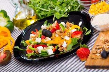 Fresh ingredients for preparation of vitamin salad from arugula and vegetables on striped textile background..