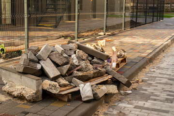 Construction waste lies on the sidewalk. Lots of stones and concrete products