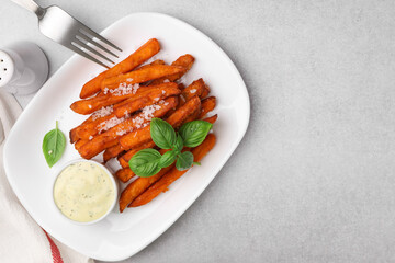 Sweet potato fries, basil and sauce on light grey table, top view. Space for text
