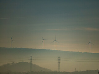 Strommasten und Windräder im Nebel in der Ferne