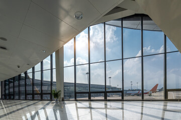 Modern Airport Terminal Interior Illuminated by Natural Light with Airplanes Outside