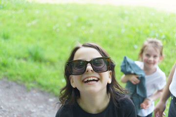 Beautiful cheerful girl in glasses and black T-shirt having fun in the summer outdoors. Concept of active mobile sincere child