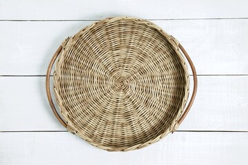 Top view of round wicker tray with wooden handles on white table. Mock-up for design, top view.