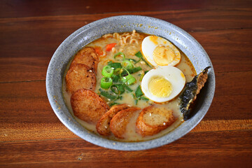Close up of curry noodle fish cake with blue bowl on the wooden table