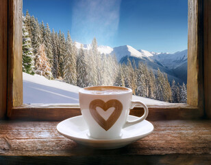 tasse de café au lait chaud avec un cœur à la montagne en hiver